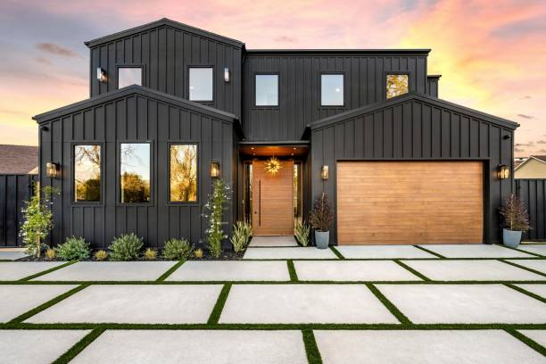 Freshly painted modern black home with vertical siding and a wood garage door by an exterior painter in Richmond, VA.